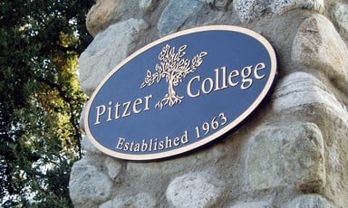 A metal placard on a stone wall says "Pitzer College, established 1963."