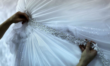 A designer puts the final touches to a wedding dress. 