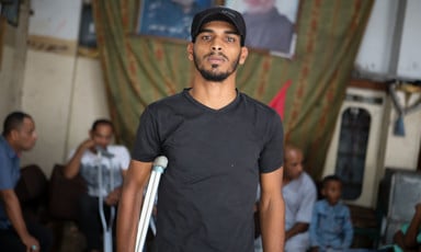 Young man using crutch is seen from waist up