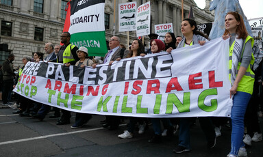 Marching near the British Parliament, protesters hold a large banner that says "Free Palestine, Stop Arming Israel, Stop the Killing"