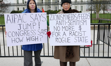 Protesters stand in front of the White House with signs reading "AIPAC says jump! Congress says how high?" and "Zionism needs/feeds anti-Semitism, no more $ for a rogue racist state"