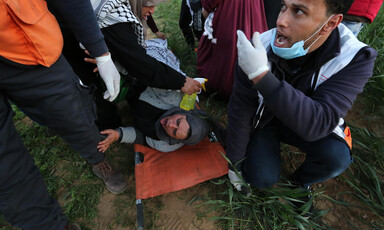 A woman on a stretcher sticks her tongue out as a woman holding a spray bottle tends to her