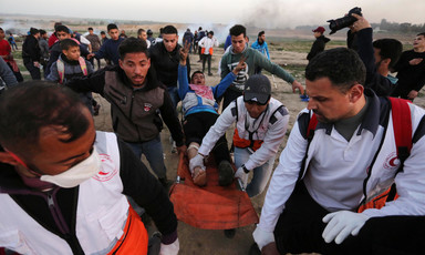 Medics carry a young man with a wounded leg on a stretcher