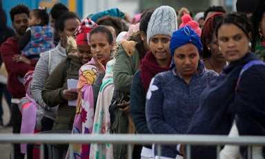 Women wearing winter clothing stand in a queue
