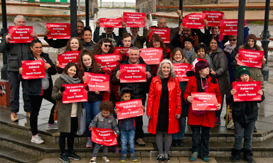 A group of Labour activists hold red signs in support of their prospective candidate for Member of Parliament.