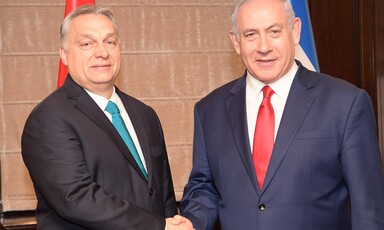 Two men in suits shake hands.