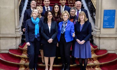 A group of people in suits pose on a staircase for unseen photographers.