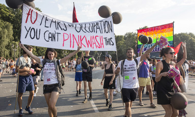 Marching young people carry a banner declaring "70 years of occupation. You can't pinkwash this"