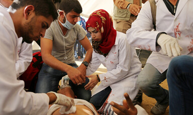 Medics treat wounded person lying on ground