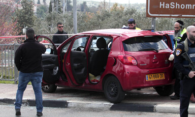 Men stand around car behind police tape