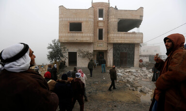 Men stand in front of two-story home with the walls destroyed on one side
