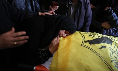A woman mourns over body of youth wrapped in a Fatah flag. 