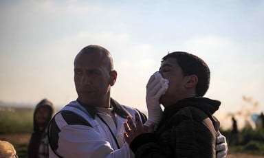 Medic presses gauze against side of man's face