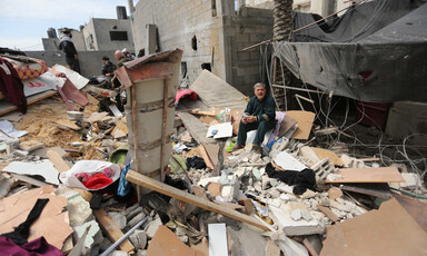 Man sits on pile of rubble and household items