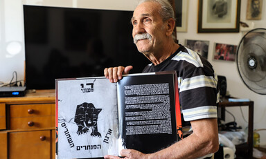 Man sits while holding a book open