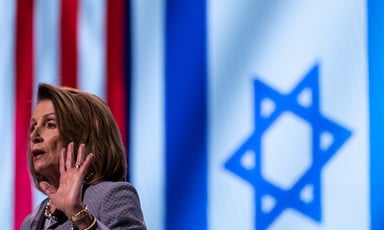 A woman at a podium in front of American and Israeli flags