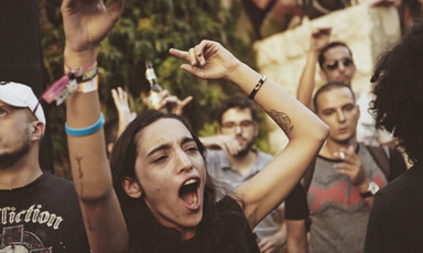 A young woman dances with her hands in the air amid crowd