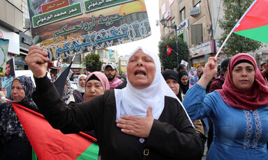 Protesters hold banners and Palestinian flags. 