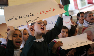 Palestinian children, adults hold banners. 