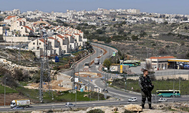 A soldier stands in front of settlement houses
