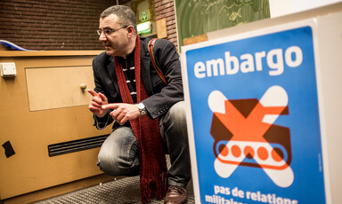 A man kneels and gestures as he speaks