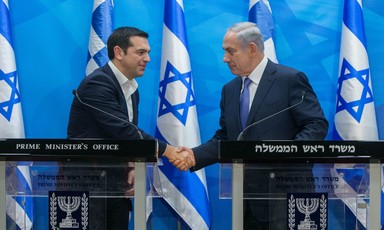 Leaders of Greece and Israel shake hands in front of Israeli flags