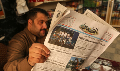 A man reads an Arabic-language newspaper in a shop