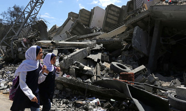 Two girls walk past rubble