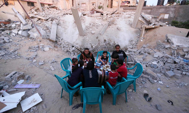 People sit around a table eating surrounded by rubble