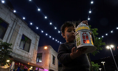 Child holding up a lantern and looking at it.