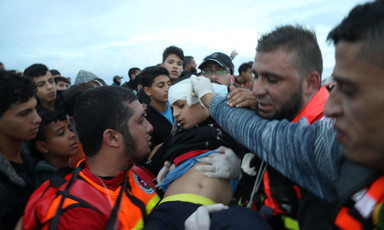 Medics hold bandage to boy's head as they carry him through crowd