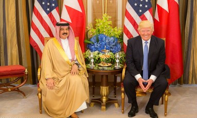 Bahrain King and Donald Trump sit side by side with American and Bahraini flags. 