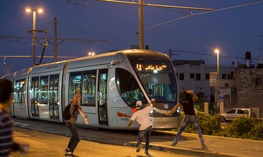 Youths throw stones at a tram