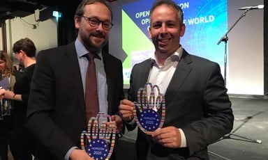 Two men smile and hold trophies that say "Horizon 2020"