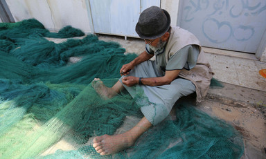 Man sits on ground with net draped over his legs