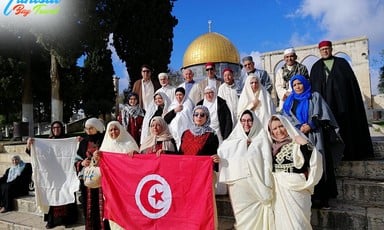 People hold the Tunisian flag near the Dome of the Rock. 