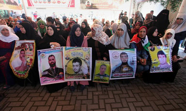 A row of women sit side by side holding banners 
