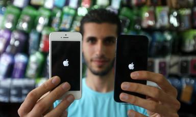 Young man holds up two iPhones in a shop