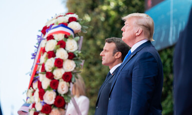 Macron and Trump stand beside a large wreath comprised of red and white roses