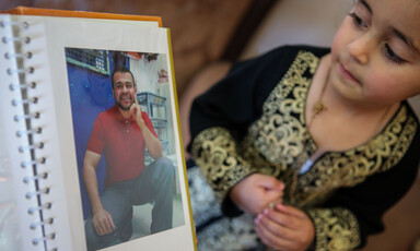 Girl looks at photo of smiling man in album