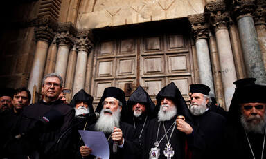 Men dressed in black robes stand side by side 