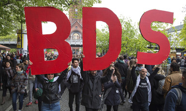 Protesters hold up big letters that spell BDS 