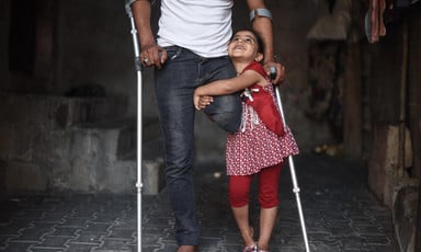 Girl hugs man using crutches seen from chest down