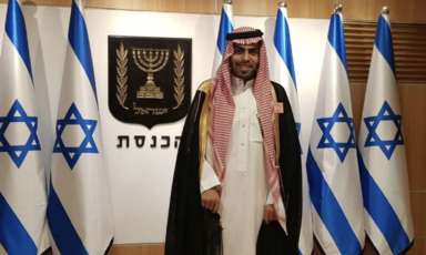 Man stands in front of Israeli flags 