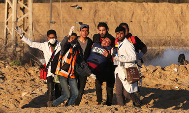 Six people, including medics, carry a man wounded in a protest.