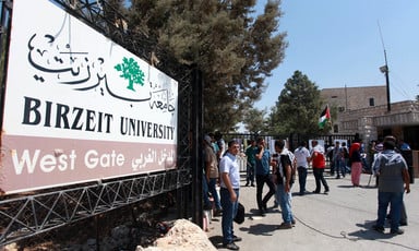 People stand near Birzeit University sign