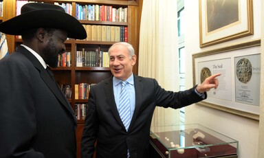 A man points to a framed picture as another looks on