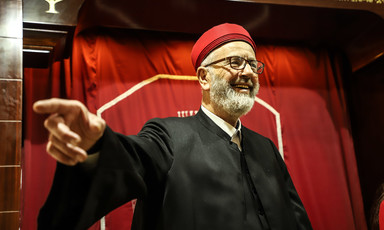 A man in religious garb gestures and smiles