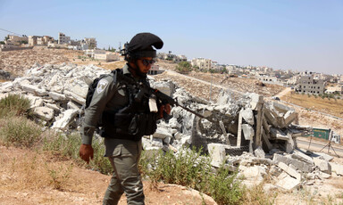 Soldier walks beside demolished building