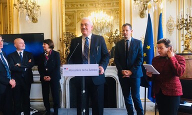 Man stands at podium with other people around him